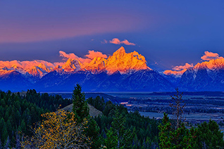 Alpenglow light illuminates the snow capped Teton peaks in Grand Teton National Park